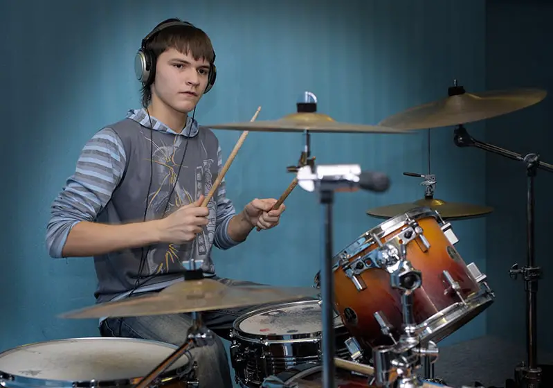 Drum student with headphones playing along to music.